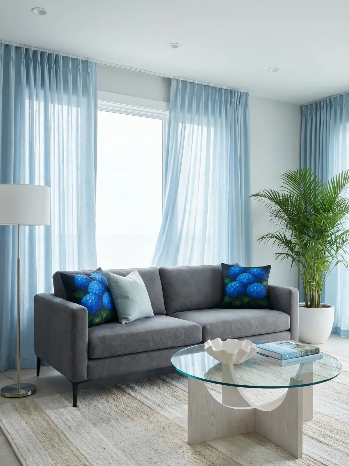 Coastal contemporary living room with light blue curtains, charcoal sofa, and blue hydrangea floral pillows