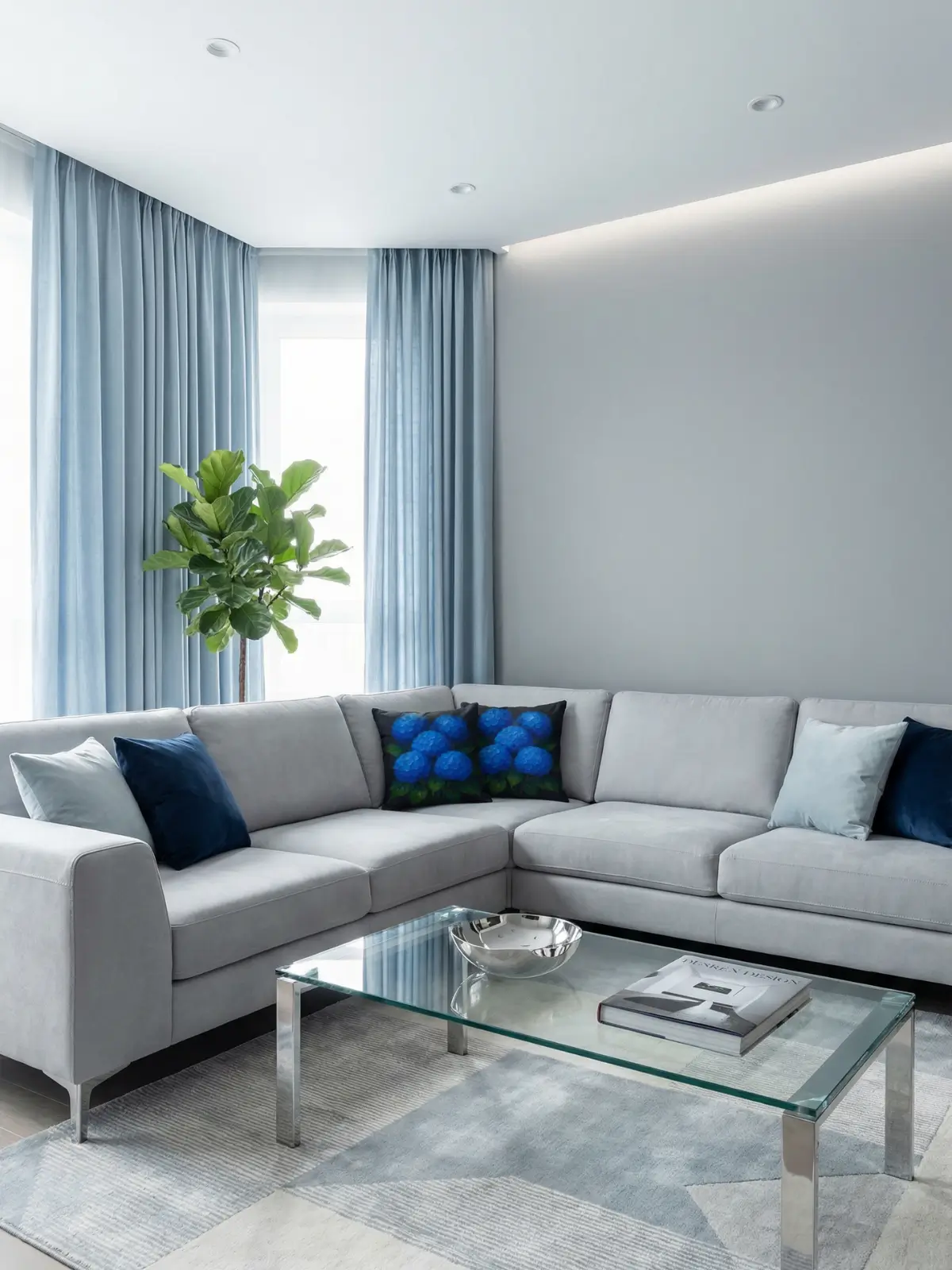 Modern living room with light blue curtains, L-shaped glacier gray sofa, and blue hydrangea charcoal floral pillows